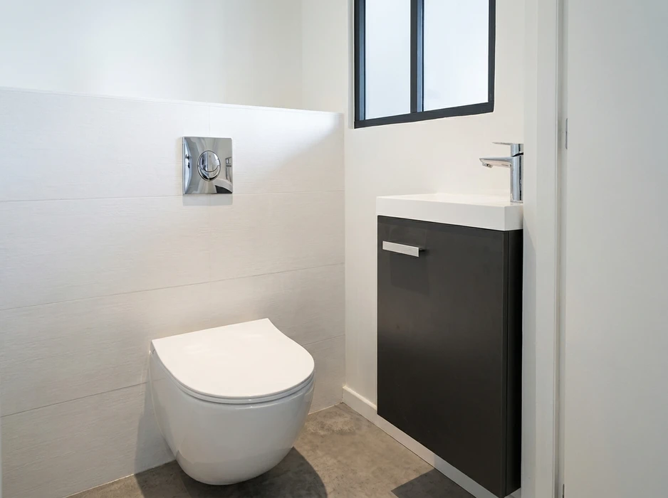 WC suspendu blanc avec abattant, dans des toilettes modernes carrelées blanc