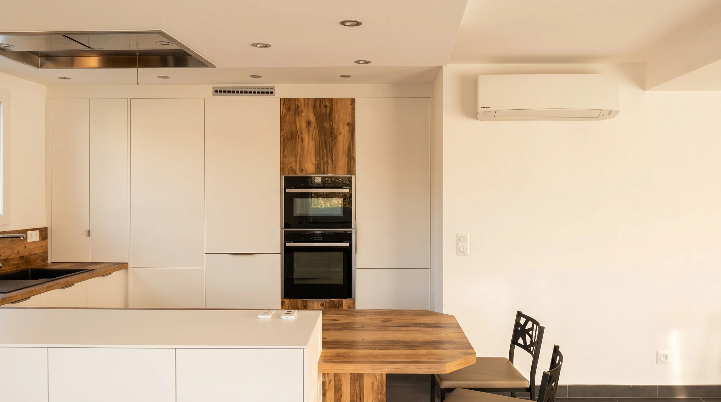Cuisine moderne ouverte, style épuré blanc mat avec plan de travail et éléments en bois massif noyer