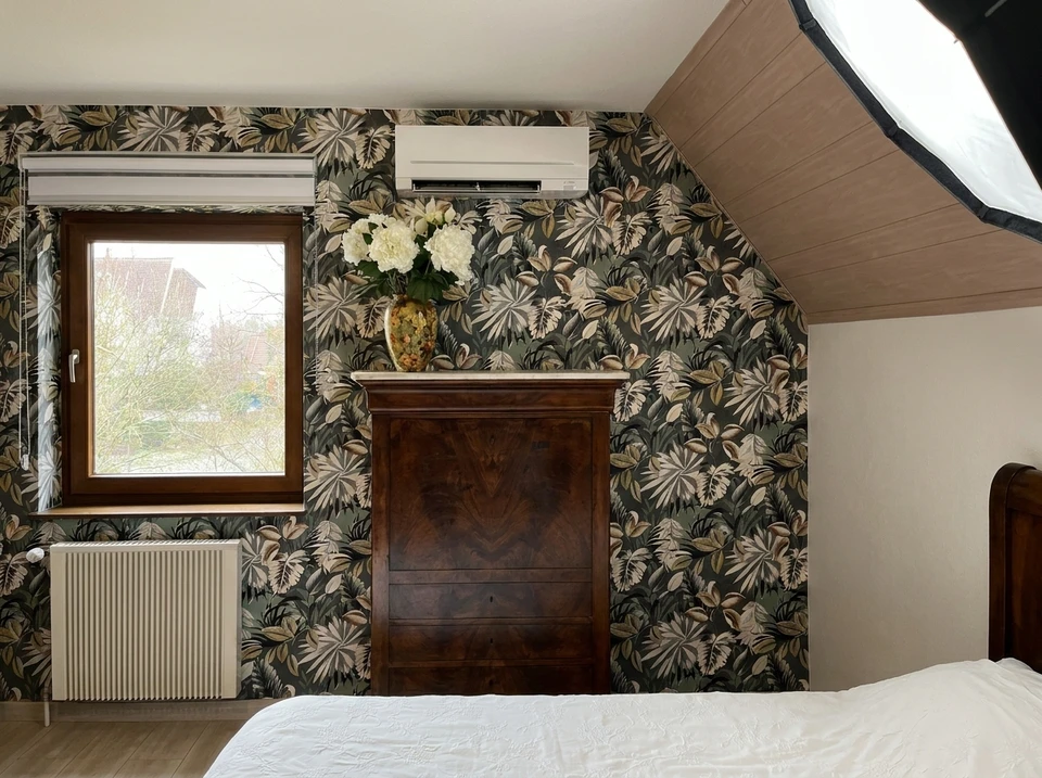 Main apposant un thermostat programmable blanc sur mur intérieur