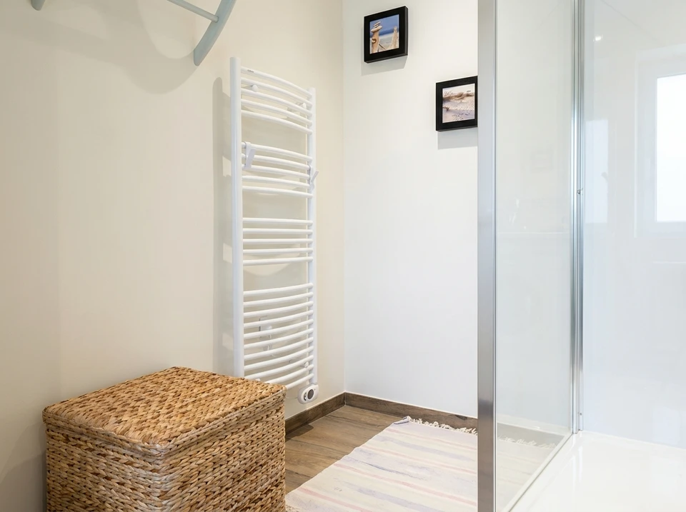 Photographie d'un chantier de r&eacute;novation montrant plusieurs professionnels en tenue de travail professionnelle coordonn&eacute;e intervenant simultan&eacute;ment sur diff&eacute;rents syst&egrave;mes&nbsp;: un &eacute;lectricien installant un tableau &eacute;lectrique mural, un chauffagiste effectuant la mise en place d'une pompe &agrave; chaleur, et un plombier raccordant des tuyauteries. La sc&egrave;ne doit montrer la collaboration et la coordination sur un m&ecirc;me espace int&eacute;rieur (cuisine ou salon en r&eacute;novation), avec des &eacute;quipements modernes visibles, illustrant ainsi la capacit&eacute; de l'entreprise &agrave; g&eacute;rer plusieurs corps d'&eacute;tat sous une m&ecirc;me coordination.